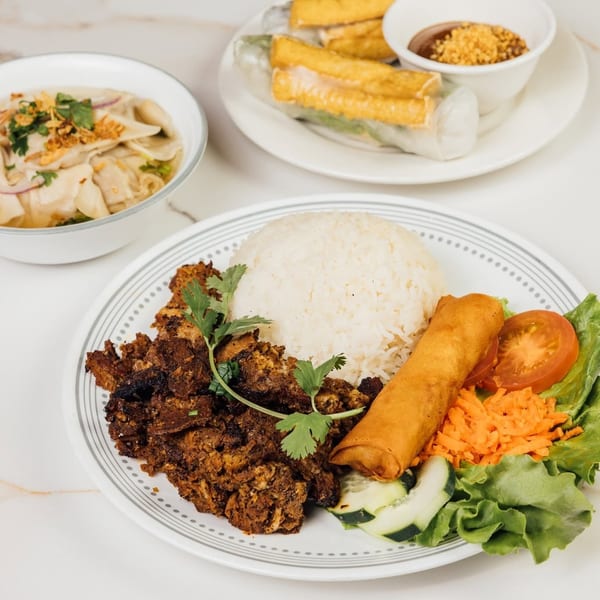 Platter of grilled meat, rice, spring roll, salad, with fresh rolls and noodle soup.
