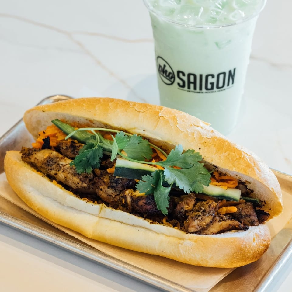 Chicken banh mi sandwich on a tray with an iced green drink from Pho Saigon.